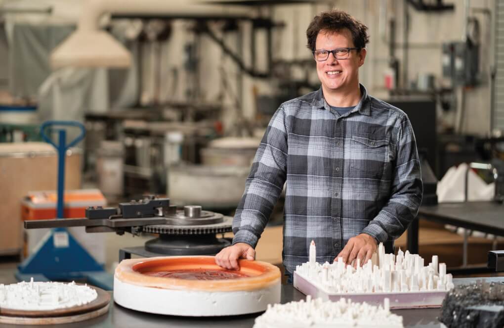 Norwood stands in the studio with his molds and forms in front of him 